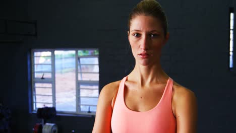 Portrait-of-woman-in-sportswear-standing-in-gym