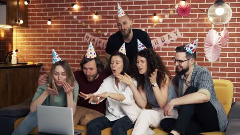 cheerfur friends at home celebrating birthday having video call by laptop