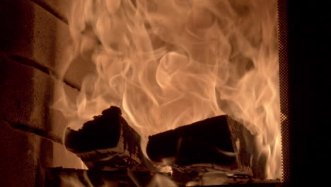 close up shot of a roaring fire burning large logs, high golden orange flames