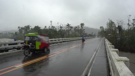 vehicles on wet asphalt road during typhoon rai in southern leyte, philippines. wide shot