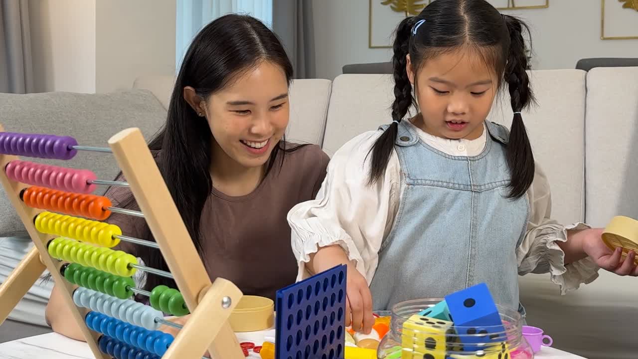 家で、母親と幼い娘がカラフルなそろばんと積み木で遊んでいる。