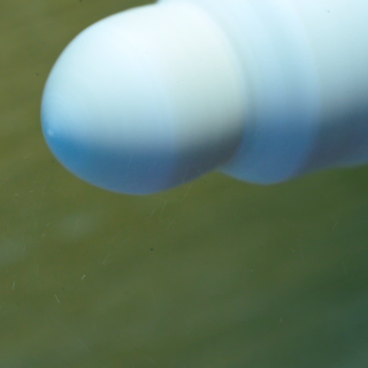 Eye prosthesis is polishing by a special instrument. Hands in gloves holding artificial plastic eye near the polishing machine. Close-up.