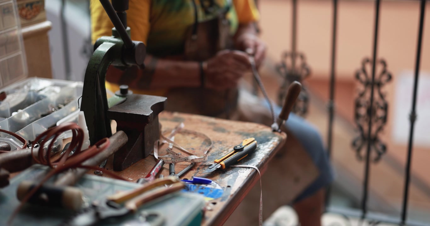 Artisan's Workbench with Tools and Hands Working in Background