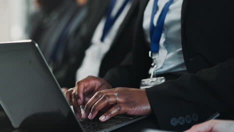 a business woman typing on a laptop at a conference.