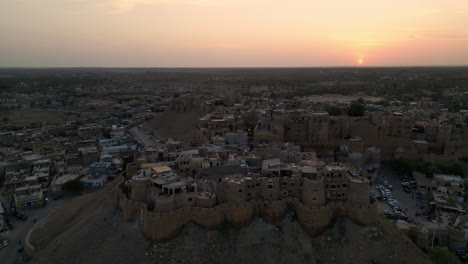 orbit drone shot of jaisalmer fort surrounded by houses at evening with vibrant sky 4k view, rajasthan, india