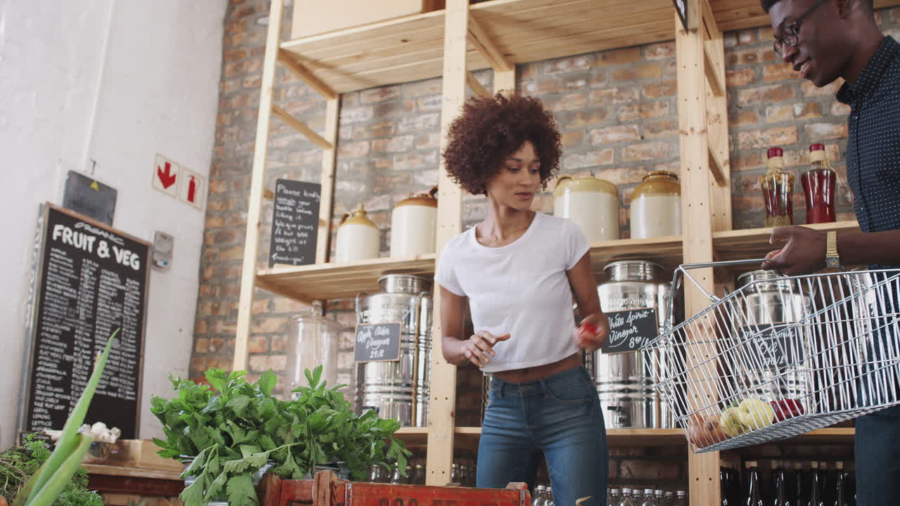una pareja joven compra frutas y verduras frescas en una tienda de comestibles sostenible sin plástico