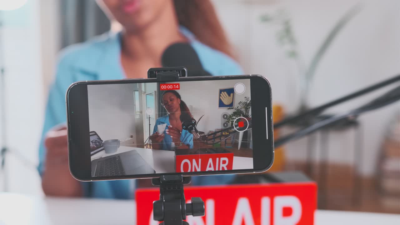 Young beautiful african american woman blogger with cream records video at phone