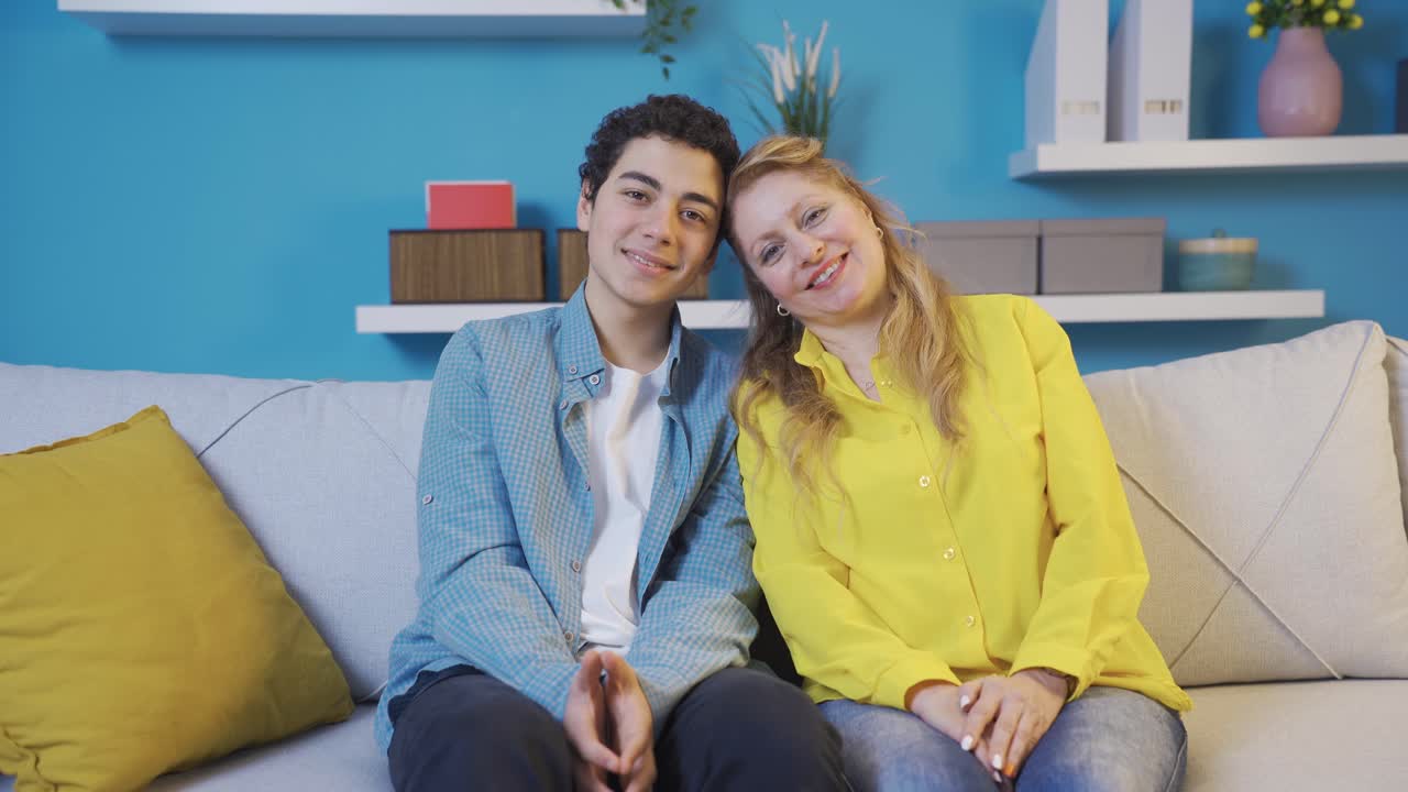 madre y hijo felices y alegres mirando a la cámara y sonriendo en su hogar moderno.