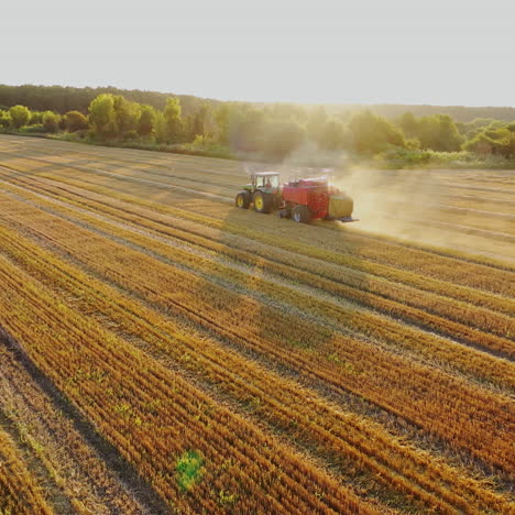 tractor is collecting dried grass on the beautiful field background. agricultural machine at seasonal works in summer. motion camera forward.