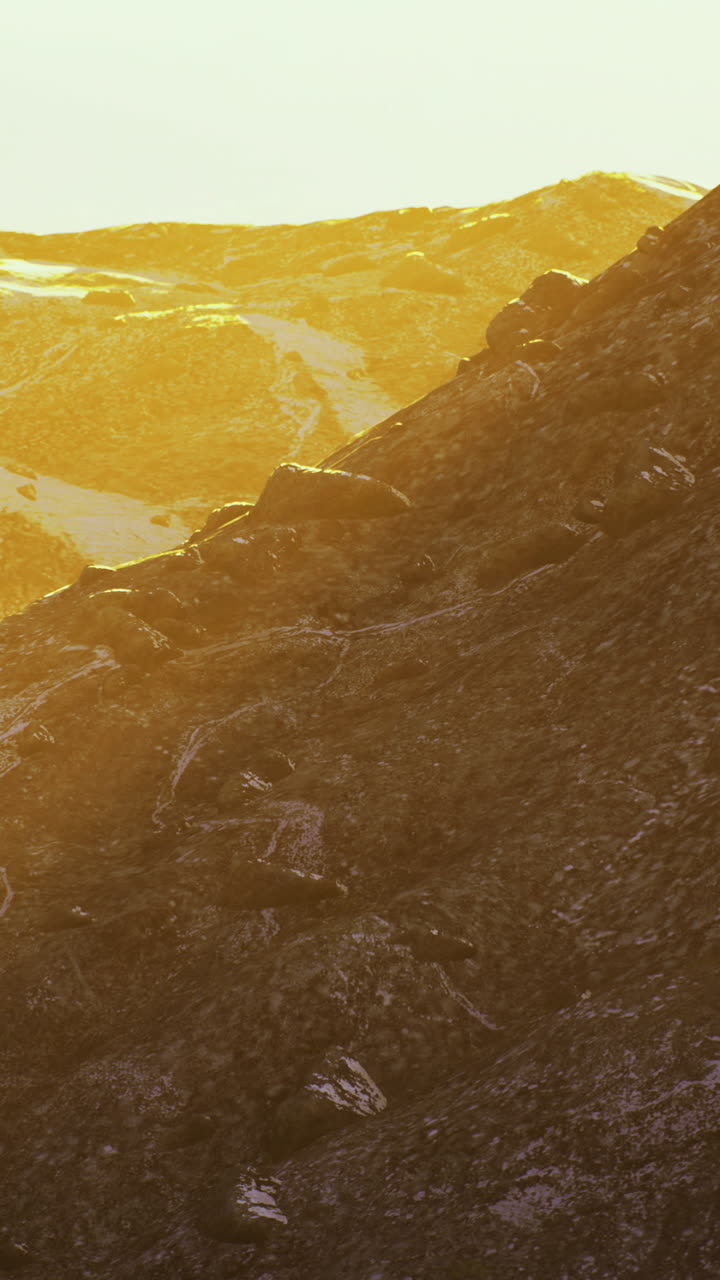 Golden sunlight bathes rugged mountain terrain at sunset