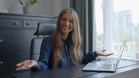 Young-woman-in-a-modern-elegant-grey-office,-turning-and-looking-into-camera,-with-a-welcoming-smile-and-eye-contact