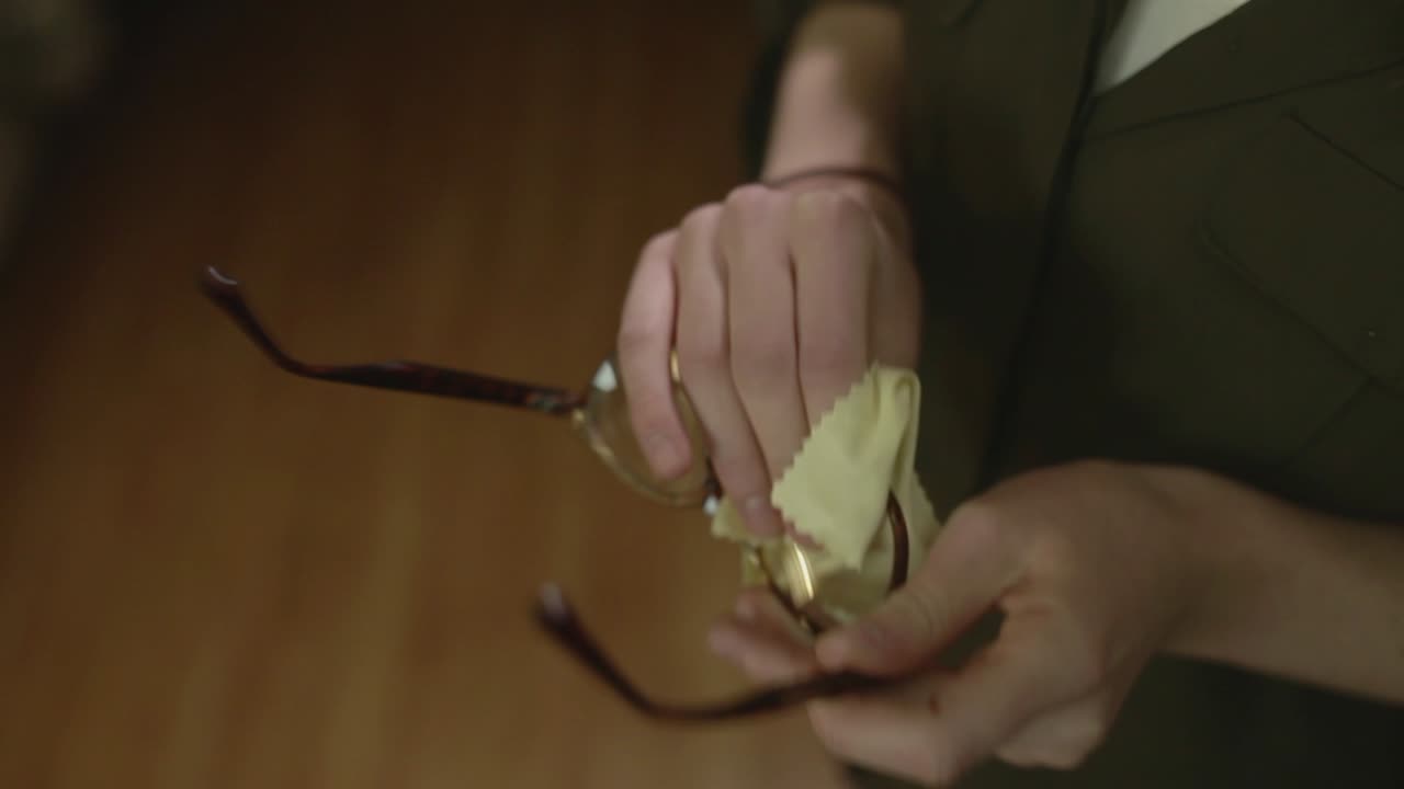 A young woman cleans her glasses