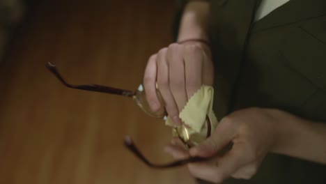 a young woman cleans her glasses
