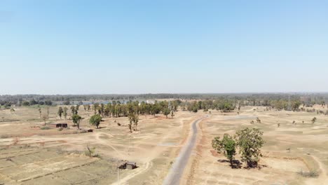 Toma-Aérea-De-Tierra-árida-Y-árida-Con-Carretera-Asfaltada-Y-Agua-A-Distancia-En-La-Aldea-De-Charu-En-Chatra,-Jharkhand,-India