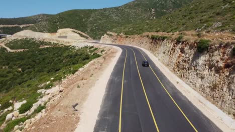 Black-car-driving-on-newly-asphalted-road-with-yellow-lines