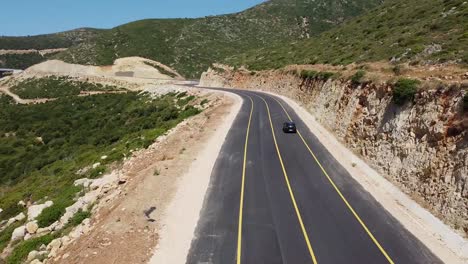 Coche-Negro-Conduciendo-Por-Una-Carretera-Recién-Asfaltada-Con-Líneas-Amarillas