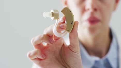 video of caucasian female doctor holding hearing aid, selective focus