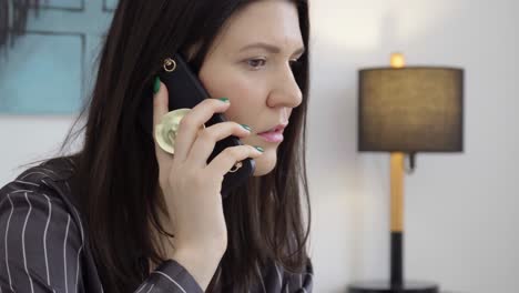 close up of woman in the bedroom wearing black pajamas speaking by cellphone