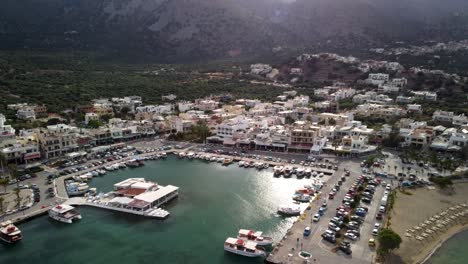 Sonnenlicht-Spiegelt-Sich-Im-Yachthafen-Von-Elounda-Auf-Der-Insel-Kreta-Mit-Den-Hohen-Bergen-Im-Hintergrund