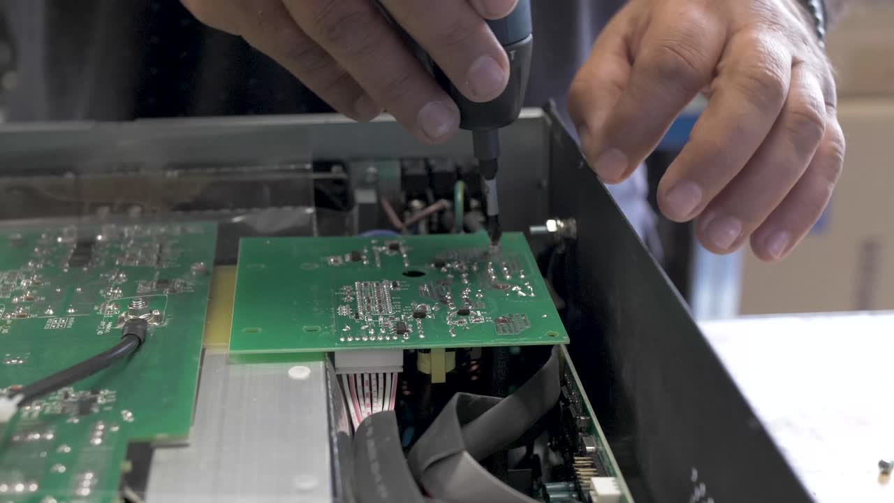 Technician unscrewing and disassembling a solar inverter box with a screwdriver, Close up shot