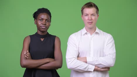 dos jóvenes parejas de negocios multiétnicos con los brazos cruzados juntos
