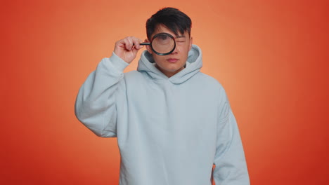 investigator researcher man with magnifying glass near face looking into camera with big zoom eye