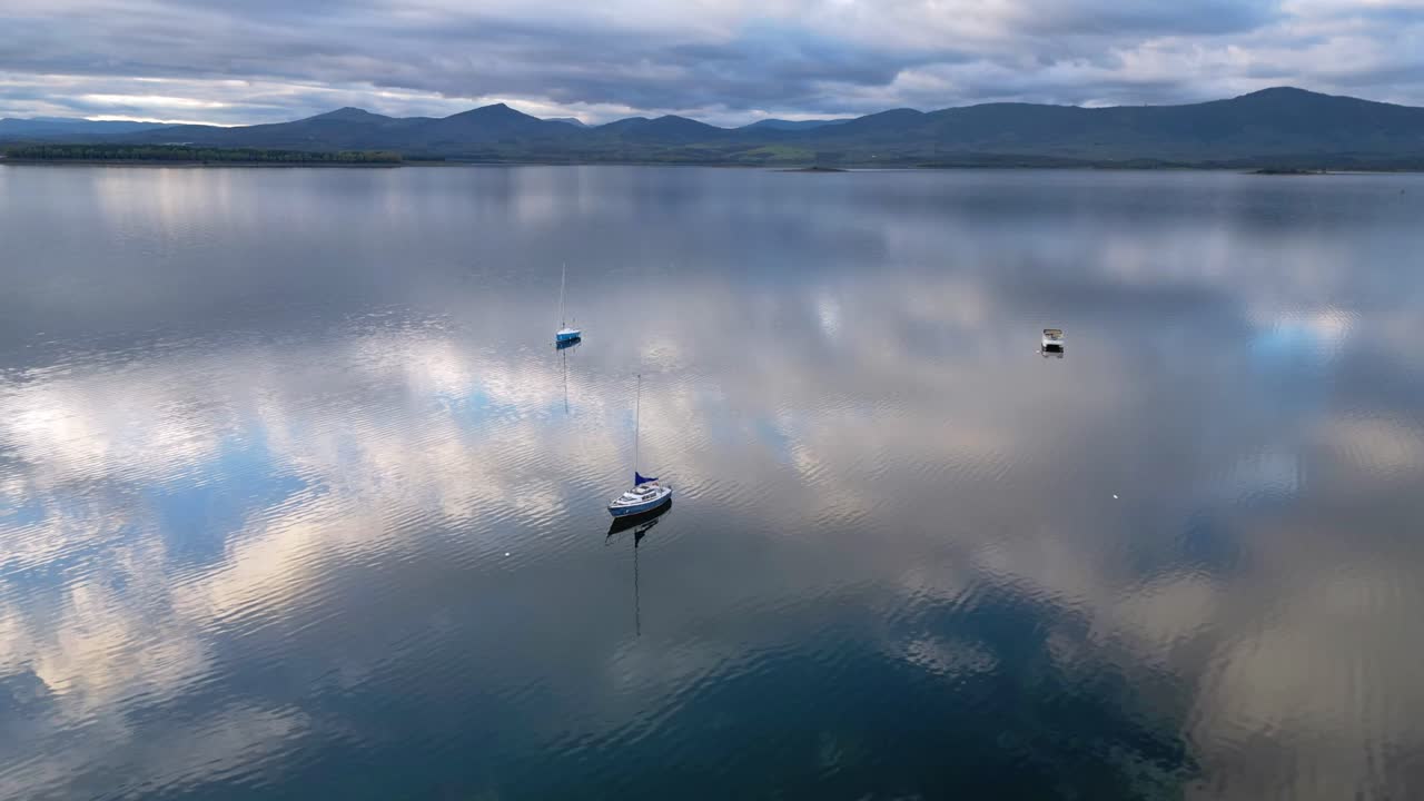 Hyperlapse of boats moving across a reservoir in Extremadura, Spain. Wide inland water landscape with peaceful rural surroundings