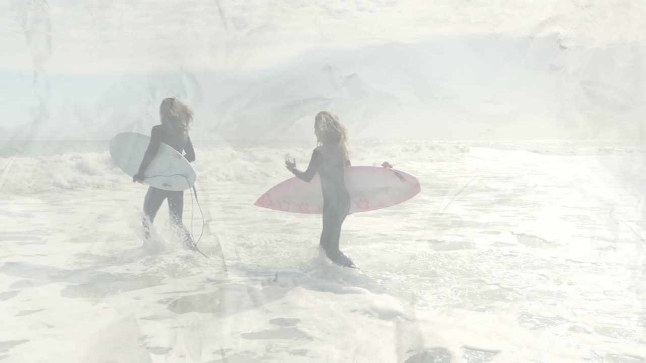 Two surfers wearing wetsuits walking into surf, carrying boards with animated wave icons for sports