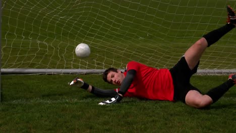 goalkeeper in red letting in a goal during a game