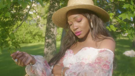 Mujer-Negra-Ajustando-El-Cabello-En-Un-Picnic-En-El-Parque-Mirando-Hacia-Otro-Lado-En-ángulo-Bajo