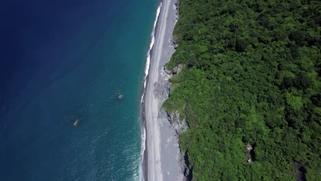 tropical beach covered in fallen boulders from gradual cliff-side erosion on the eastern coast of taiwan - gradual gimbal tilt up