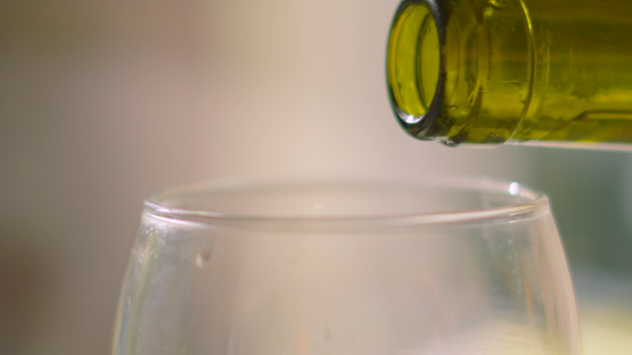 Chilled French White Wine Being Poured from Bottle in Ultra Slow Motion with Shallow Depth of Field. Refreshing Alcoholic Beverage.