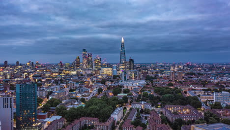 Fliegen-Sie-Am-Späten-Nachmittag-über-Die-Städtische-Nachbarschaft,-Hyperlapse.-Auf-Dem-Weg-Zu-Den-Wolkenkratzern-In-Der-Innenstadt.-Das-Licht-Wird-Ausgeblendet-Und-Die-Sichtbarkeit-Der-Lichter-Der-Stadt-Erhöht.-London,-Vereinigtes-Königreich