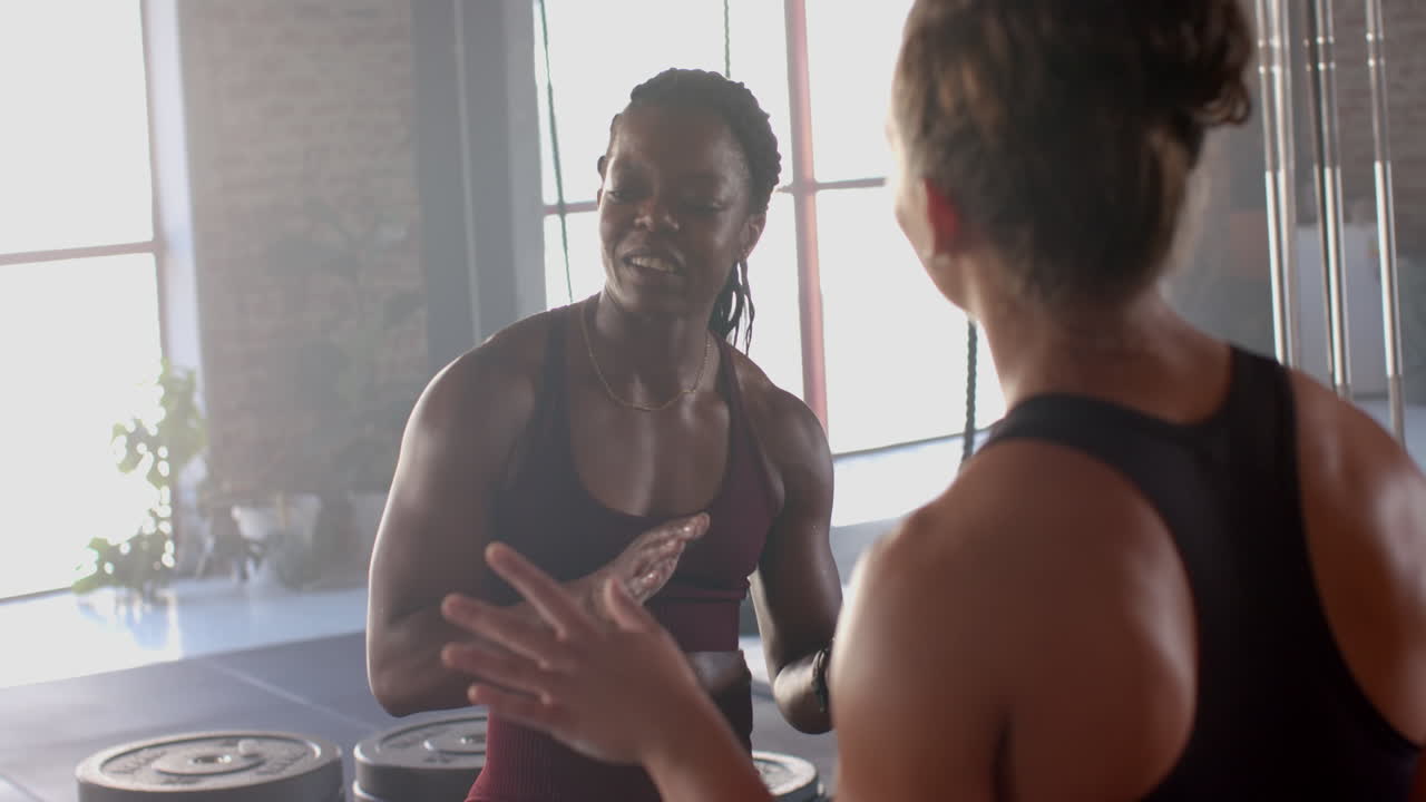 Discussing workout routine, women in gym wearing sportswear, focusing on fitness