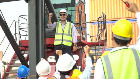 foreman manager standing on forklift speech to containers worker excited and raised hand up to success in morning meeting . group of labor celebrate at warehouse logistic in cargo freight ship port