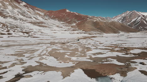 A-drone-glides-above-a-pristine-snowy-valley-nestled-in-the-heart-of-the-Andes,-bridging-Argentina-and-Chile