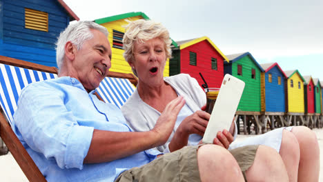 senior couple using digital tablet at the beach