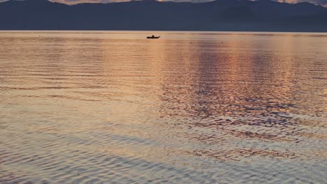 Reveal-shot-of-Lake-Atitlan-Guatemala-with-fishing-boat-during-sunrise,-aerial