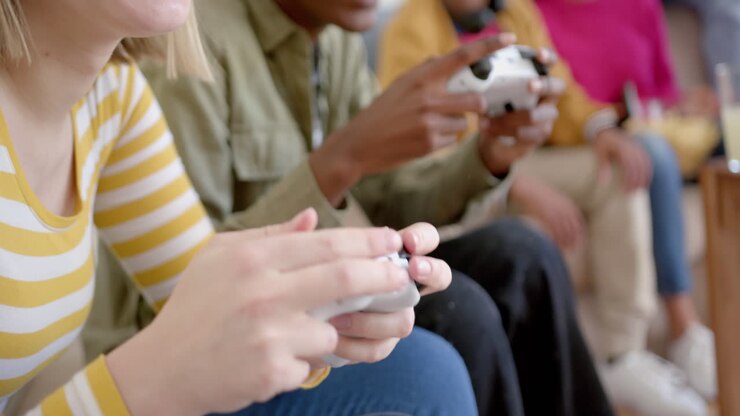 Happy diverse group of teenage friends sitting on couch and playing video games at home, slow motion