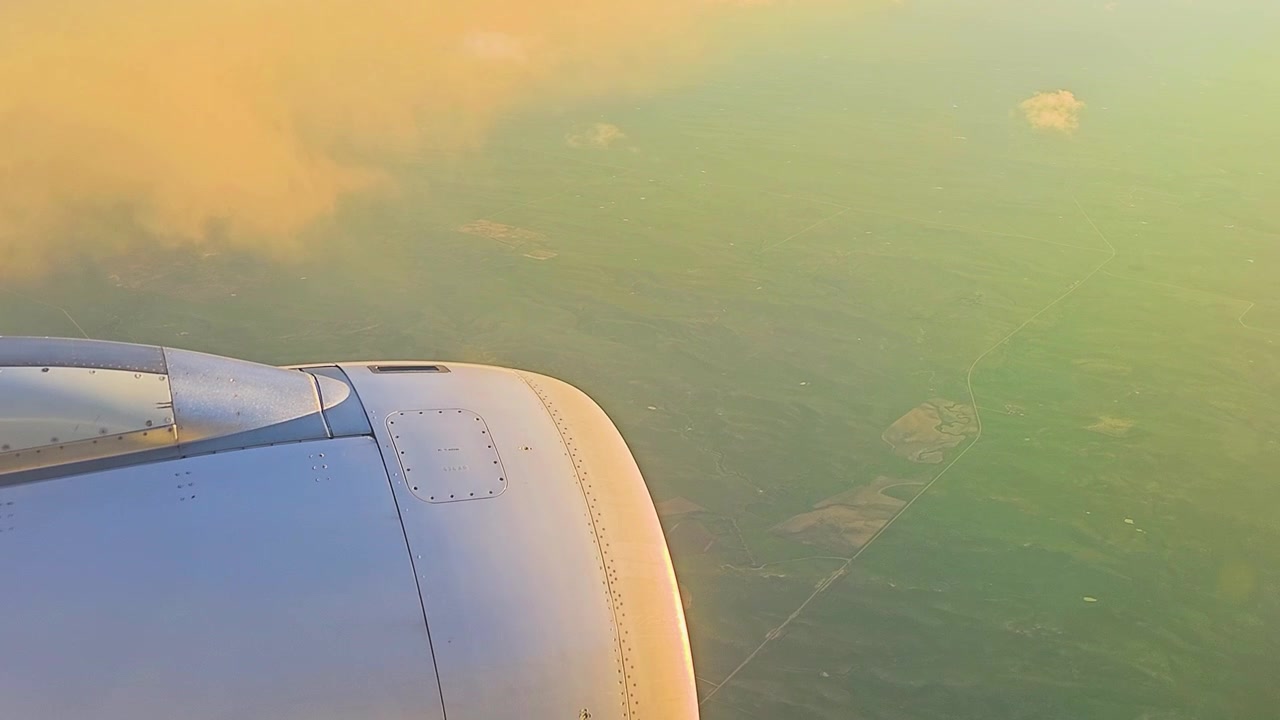 Flyvinge og motor over lappetappefelt idet sollys bryter gjennom skyene, utsikt fra vinduet på et flygende fly i stor høyde, opptak fra flyreise, POV