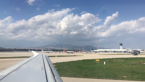 wing view from an airplane at the airport looking other airplanes and the airport buildings and land