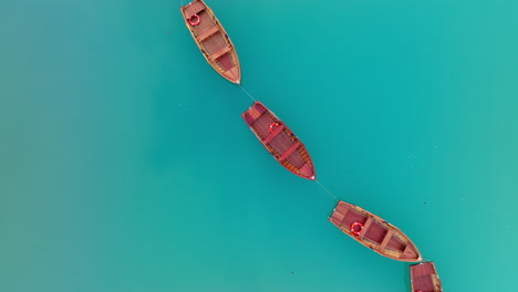 overhead view of red wooden rowboat floating attached in line on dolomites lake braies in quiet natural light