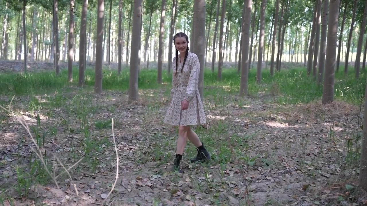 Eleganza nella natura, una donna cammina con grazia attraverso un bellissimo e sereno paesaggio forestale.
