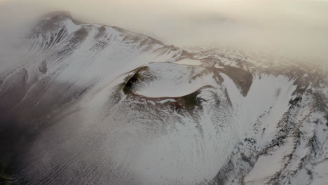 aerial: slow panning shot over a snowy crater in iceland