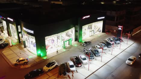 Aerial-Flyover-Luxury-Car-Company-Showroom-In-Riyadh-At-Night,-4K-Drone