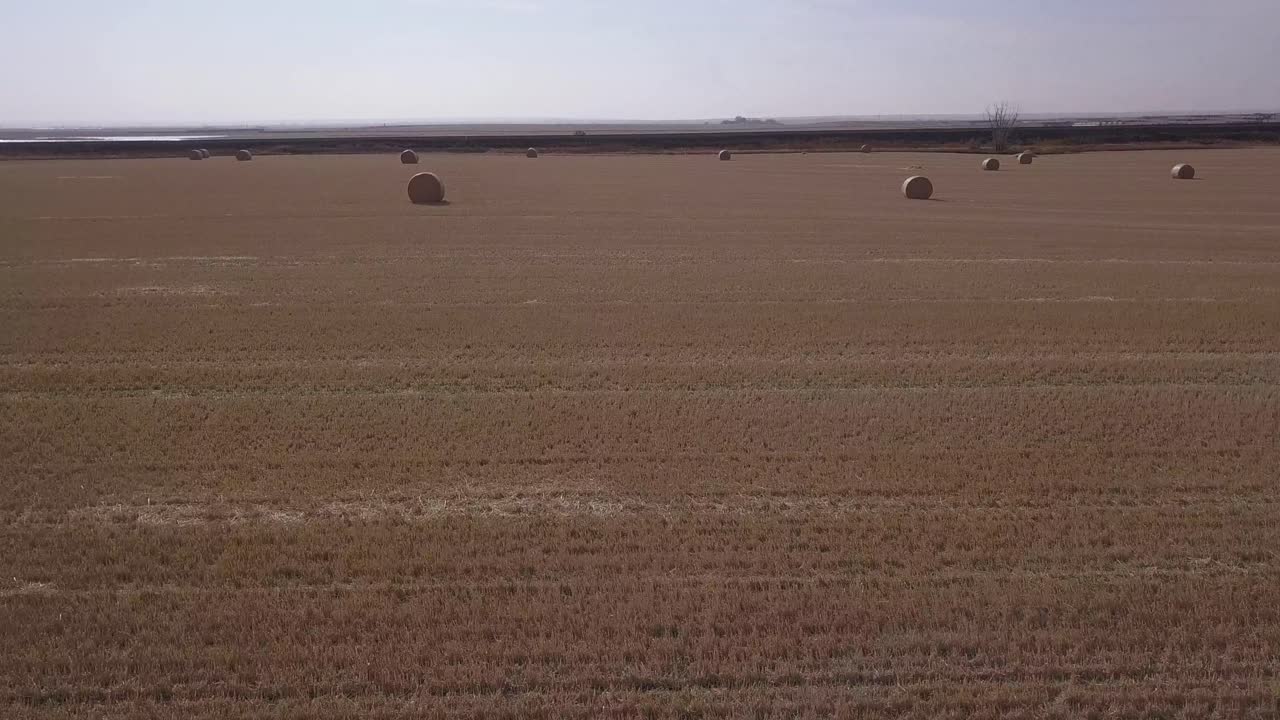 Artsy whip arc aerial of golden hay bales in fresh cut prairie field