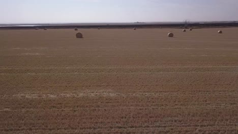 Artsy whip arc aerial of golden hay bales in fresh cut prairie field