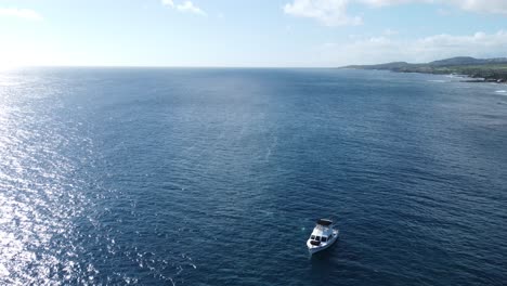 impresionante vista aérea capturando una playa, un barco, el océano azul y el paisaje montañoso
