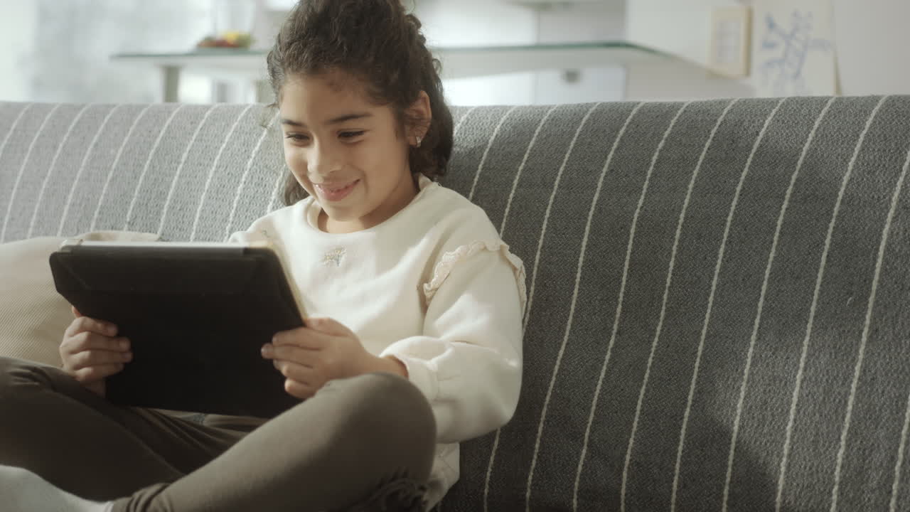 Little Girl Watching Cartoon on Digital Tablet at Home