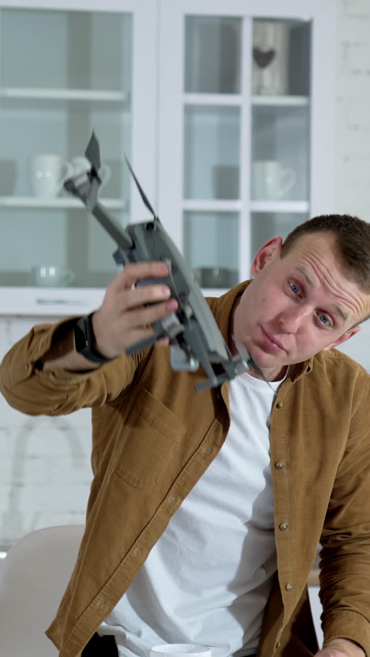 Kyiv, Ukraine, 2 May 2025: Young Man Showing Drone. Man playing with professional drone in room. Vertical video